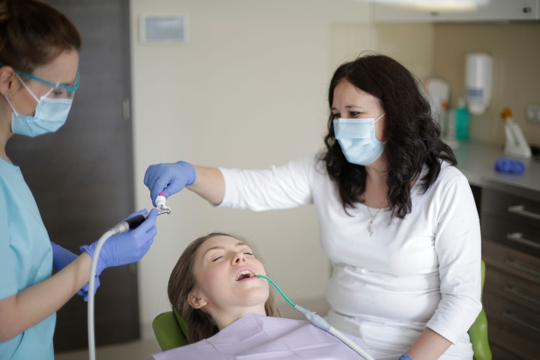 Dentist treating a cavity while the patient rests in the chair
