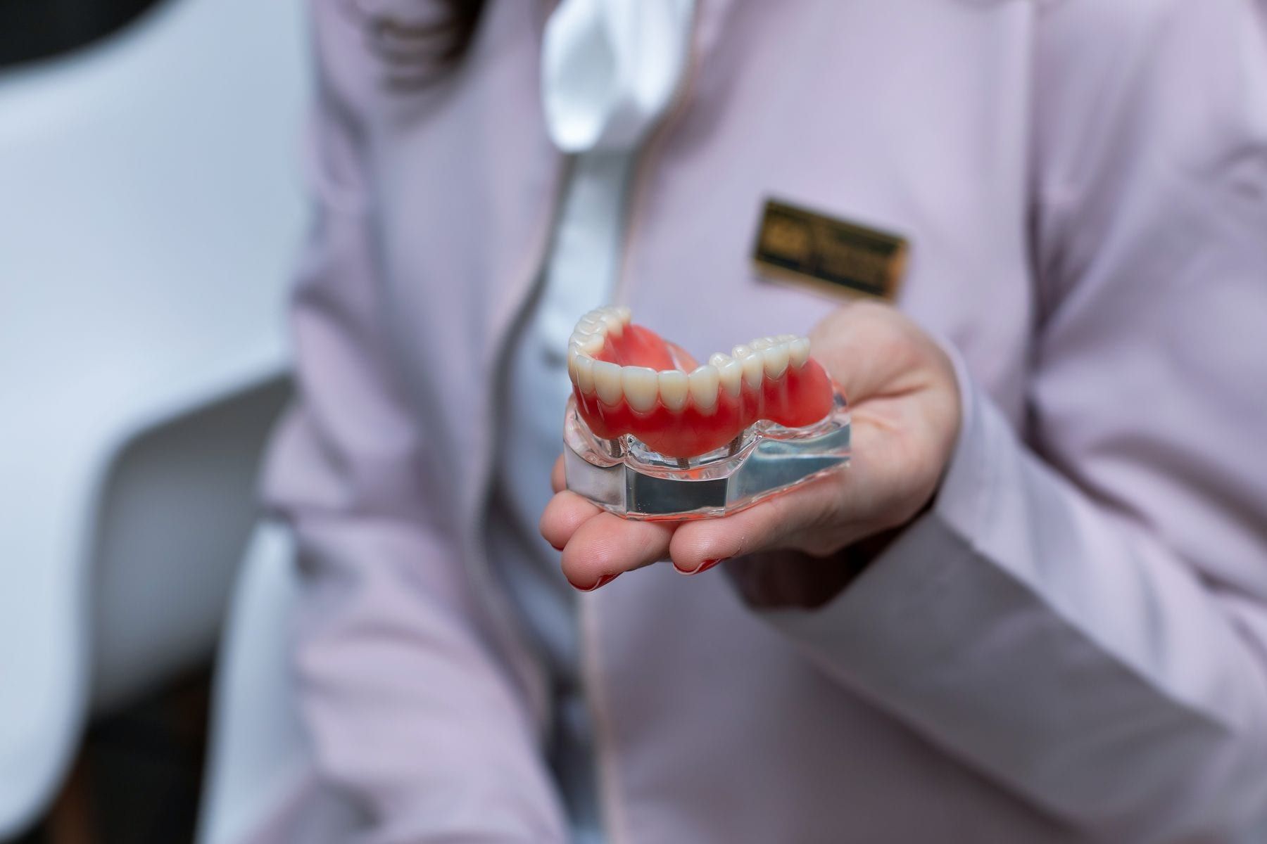 Dentist holding a model of a full set of replacement teeth